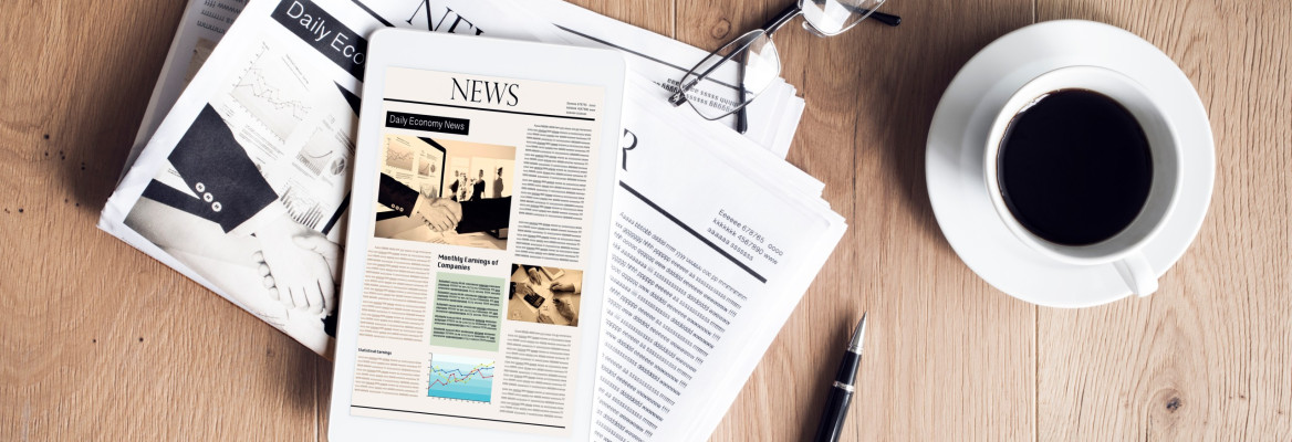 Newspaper with tablet on wooden table